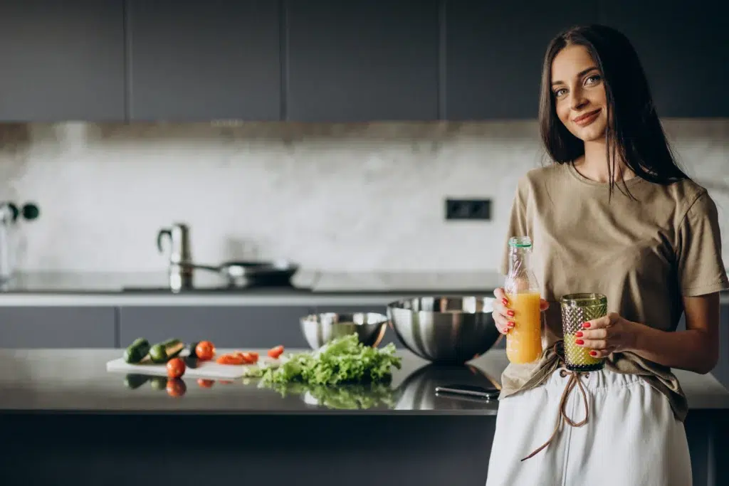 Bianca holding a glass of natural juice in her kitchen, preparing a Zepbound-friendly drink